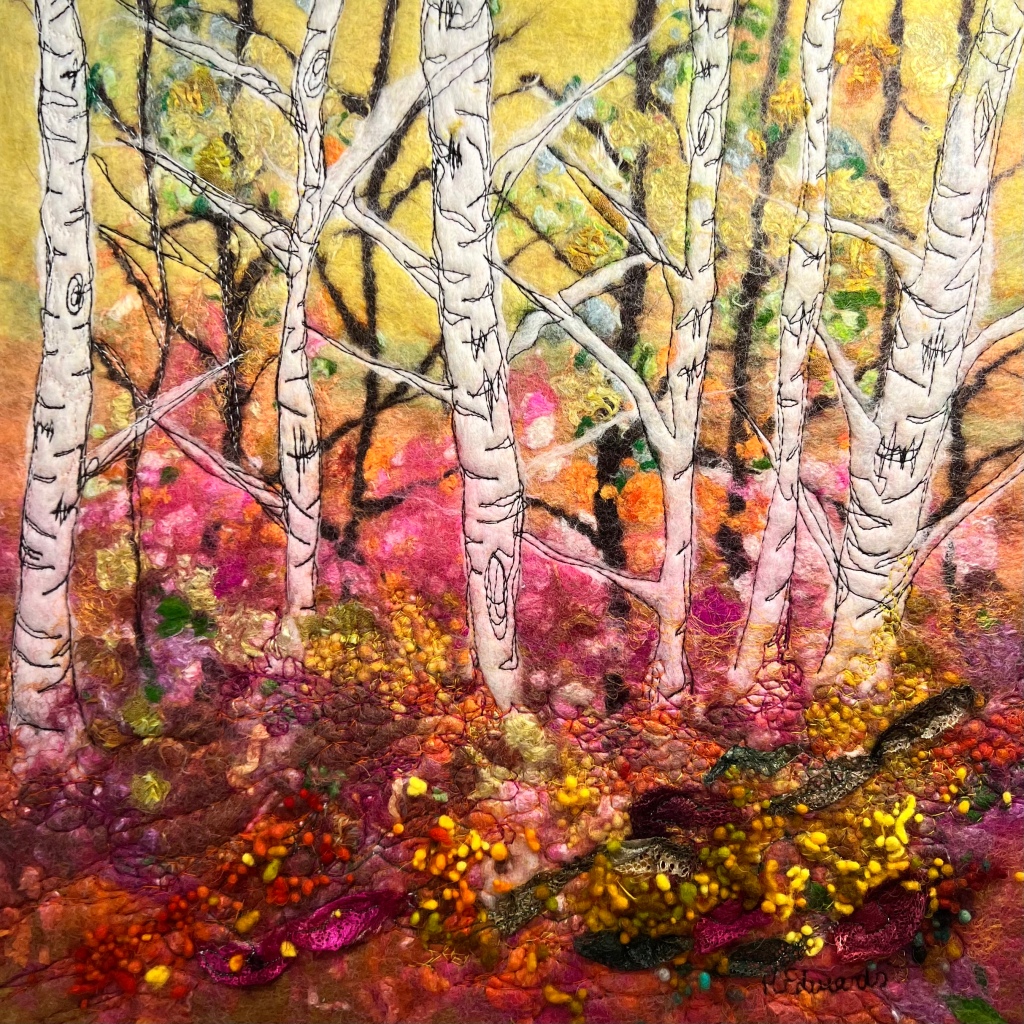 a photo of a piece of art work made from yarn and embroidery showing some trees in a forest in shades of pink, yellow and orange