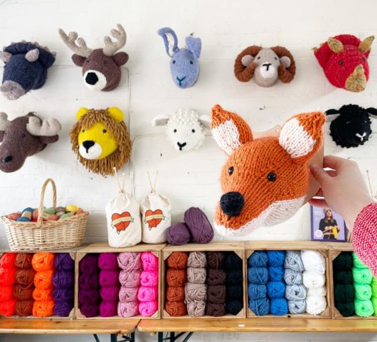 knitted taxidermy-inspired animal heads arranged on a wall 