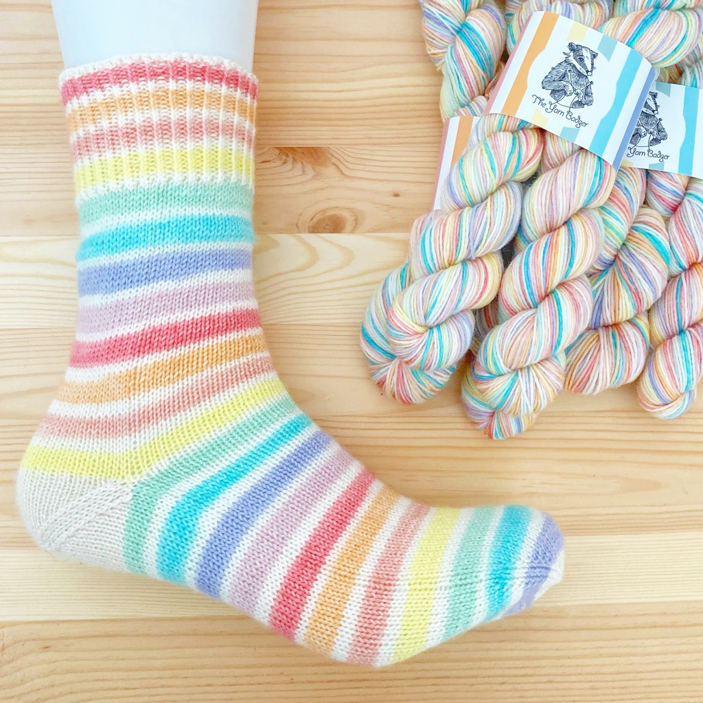 a stripey knitted sock in bright rainbow shades on a foot mannequin 