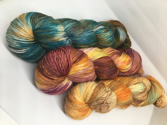 3 skeins of yarn in shades of green, brown and orange