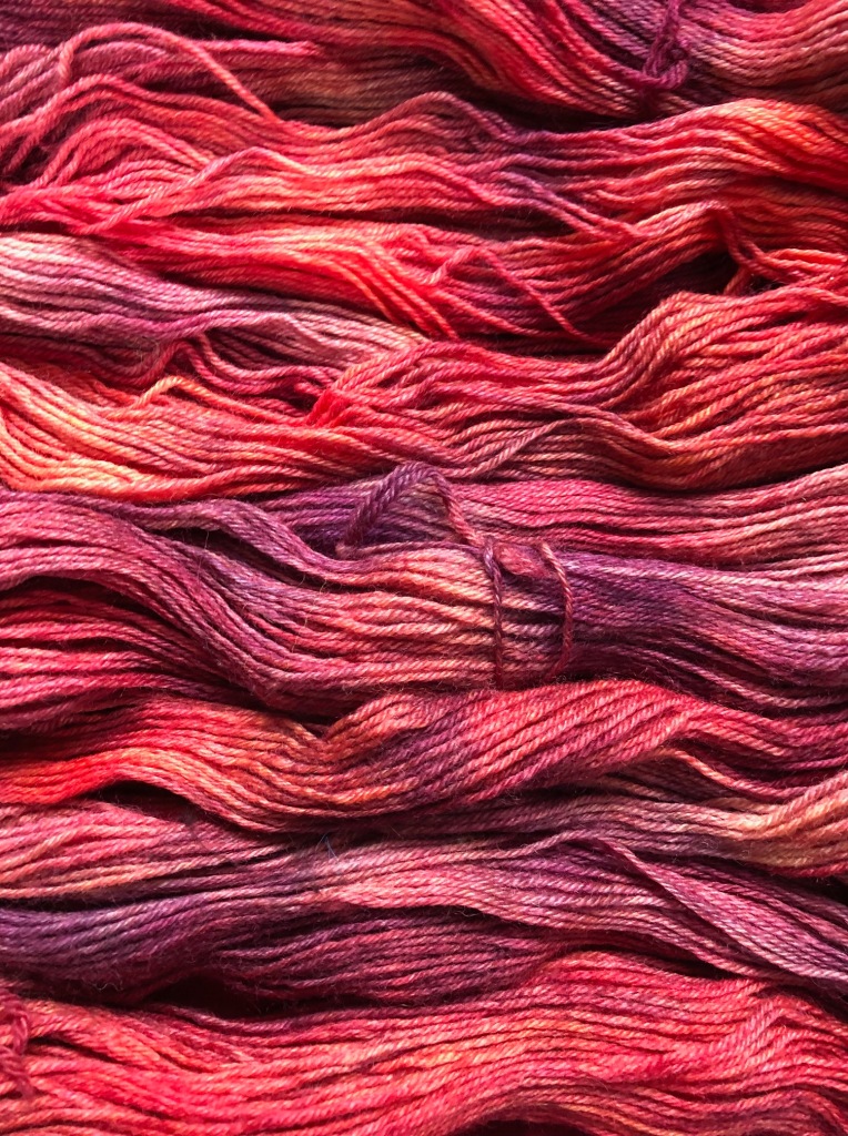 untwisted skeins of yarn dyed in rich red tones 